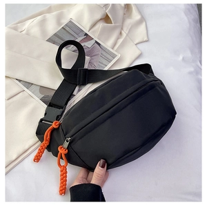 Detail of black nylon chest bag featuring vibrant orange zipper pulls and adjustable strap