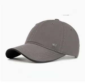 Detail view of a grey cotton baseball cap with a rectangular metal label on the side
