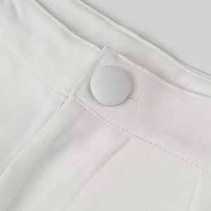 Close-up of white twill fabric waist detail featuring a matching circular button fastening