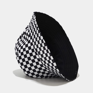 Flat lay macro of a reversible checkerboard bucket hat showing black lining and canvas texture