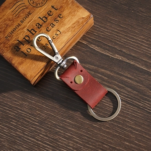 Vintage rode lederen sleutelhanger met messing ring op donker houten tafel