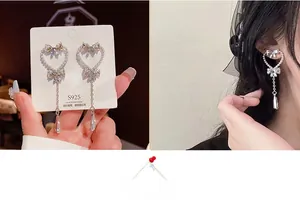 Detailed view of heart-shaped pearl bow earrings with sparkling rhinestone drop tassels