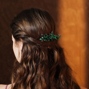 Close-up of a green crystal bridal hair comb styled on wavy brunette hair