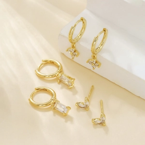Set of three pairs of 18K gold plated earrings with clear zircon stones and flower charms