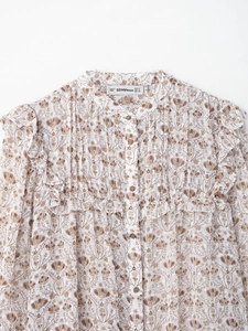 Détails des volants et de l'imprimé floral marron sur cette blouse blanche en mousseline