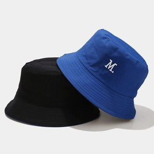 Dettaglio ricamo lettera M su cappelli alla pescatora reversibili in tela blu e nero