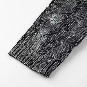 Gros plan d'une manche de pull noir en maille avec texture torsadée et détails aux poignets