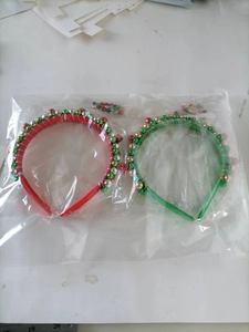 Detailed view of red and green Christmas reindeer antler headbands with bells in packaging