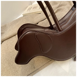 Detail of creative dark brown dachshund-shaped leather tote bag with top zipper and handles