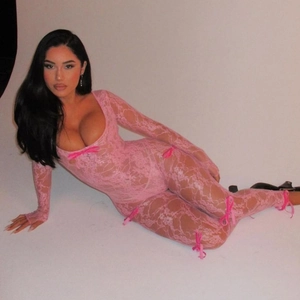 Detailed texture of pink lace bodysuit with long sleeves and delicate bow accents