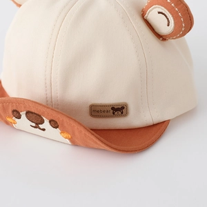 Dettaglio cappellino neonato con orecchie da orso, ricami e etichetta in pelle mebear