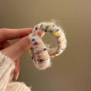 Primo piano di elastico per capelli in peluche bianco sporco con puntini colorati
