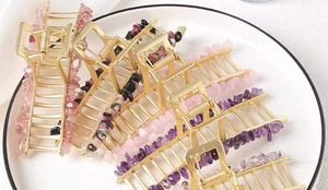 Macro shot of gold alloy hair claws with colorful natural crystal stones on a plate