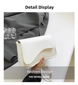 Detail view of white leather shoulder bag with asymmetrical curved flap design