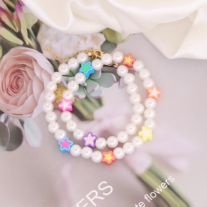 Detail of bohemian pearl necklace with colorful clay stars and gold lobster clasp