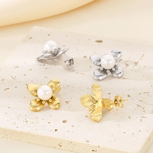 Detailed view of pearl earrings in gold and silver finish on a stone texture base