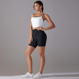 Detail of white cropped sports top and high-waisted black yoga shorts on model