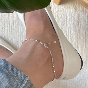 Detail of minimalist S925 sterling silver olive bead anklet on a model's ankle