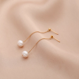 Elegant natural freshwater pearl drop earrings with gold tassels for women on pink fabric