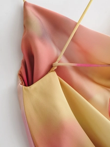 Close-up of pink and yellow gradient satin dress with soft cowl neck and strap details