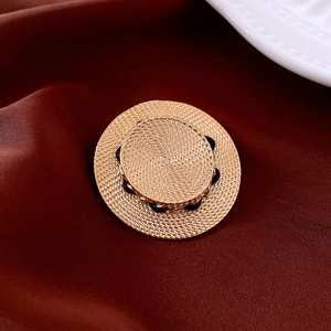 Gros plan d'une broche chapeau de paille dorée avec lignes noires ondulées