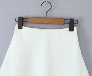 Détail d'une jupe en satin jacquard blanc avec texture florale et fermeture éclair invisible