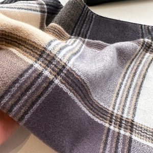 Close-up of thick plaid cashmere scarf showing soft texture and tassel detail