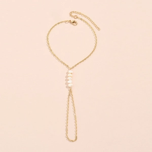 Golden baroque pearl hand chain harness with five irregular pearls on a pink background