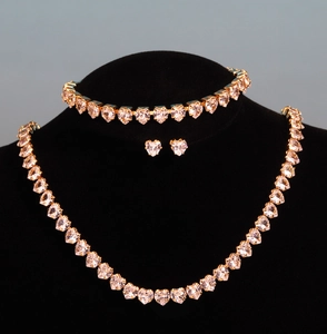 Detail shot of gold-plated jewelry set with heart-shaped pink crystals and cubic zirconia