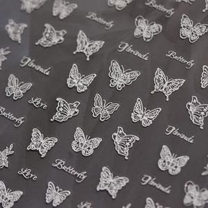 Detail of white butterfly and script nail stickers with hollow lace pattern design