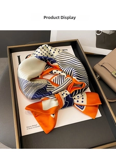 Detail of satin scarf with orange and navy geometric patterns tied as a decorative bow