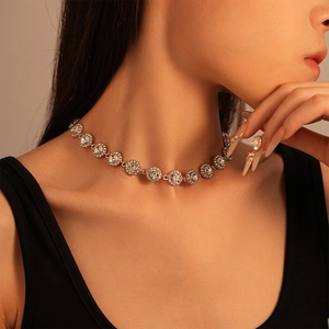 Vintage silver rhinestone circular pendant necklace worn by a model on a warm golden background