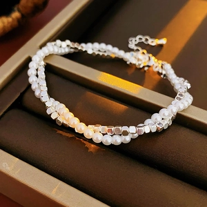 Detail of a minimalist double-layer bracelet with white pearls and silver metal square beads