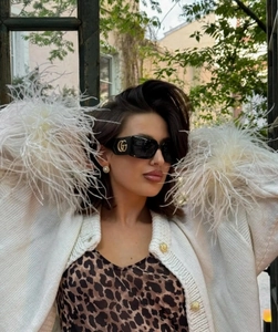 Detail der weißen Strickjacke mit Federbündchen und Oberteil im Leopardenmuster