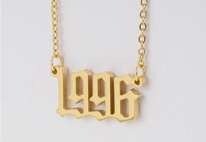 Gros plan du collier en acier inoxydable doré 18 carats avec pendentif chiffre gothique 1996