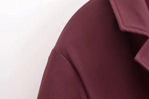 Gros plan sur le col du trench-coat bordeaux et les coutures de l'épaule