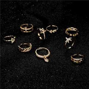 Set of 9 gold minimalist bee-themed rings with star and heart charms on black background