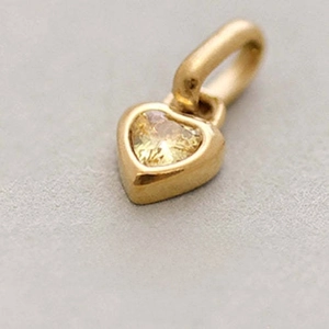 Detailed close-up of a golden heart pendant with Citrine stone for November birthdays