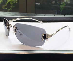 Detail of rimless Y2K sunglasses featuring a silver star hinge and gray lenses