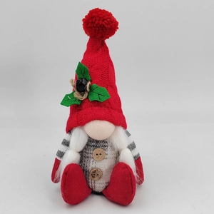 Close-up of a Christmas gnome doll with a red knit hat, holly decor, and furry white beard