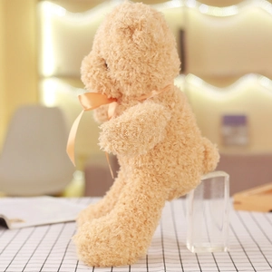 Side view of a soft light brown teddy bear skin with an orange ribbon on a checkered cloth