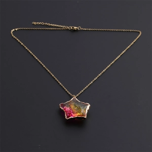 Detailed close-up of a golden chain necklace with a colorful iridescent star pendant