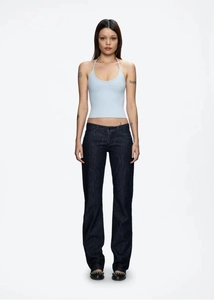 Detail shot of light blue halter neck top paired with dark blue denim jeans on a model