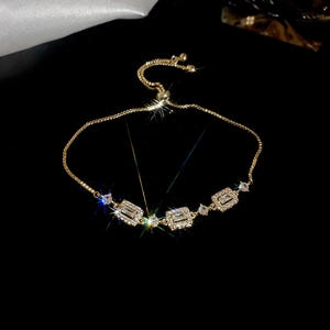 Close-up of adjustable gold-plated bracelet with rectangular zircon halos and starburst shine