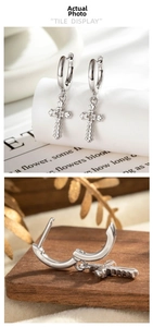 Détail de créoles en argent avec breloques croix en zircon sur support d'exposition