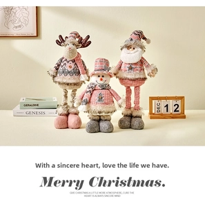 Close-up of pink and grey knitted Christmas plush reindeer snowman and Santa set