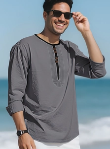 Close-up of grey cotton linen Henley shirt with black piping and buttons on beach