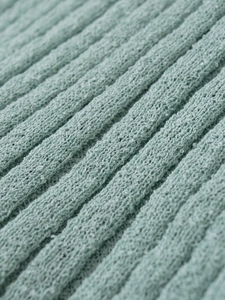 Nahaufnahme von minzgrünem Rippstrick-Stoff zeigt die weiche Textur und Stichdetails
