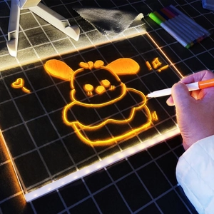 Close-up of hand drawing a cartoon character on a luminous LED tracing board