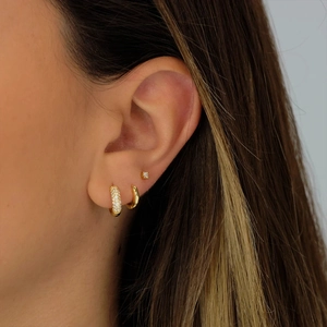 Detail of three-piece gold S925 silver Evil Eye earring set worn on a model ear